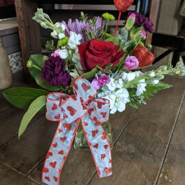 Mixed bouquet with a red rose and heart ribbon in a glass vase