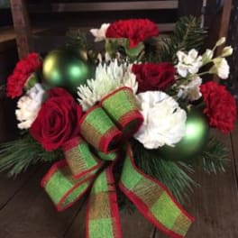 Christmas floral arrangement with red and white flowers, ornaments, and a large ribbon bow