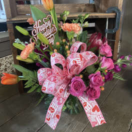 Pink and orange floral bouquet with a Valentine’s Day sign and ribbon