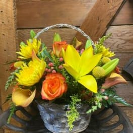 Basket arrangement of yellow lilies, orange roses, and yellow daisies