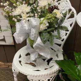 White floral arrangement with ribbon on an ornate white chair