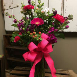 Pink and purple mixed bouquet in a glass vase with a bright ribbon