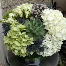 Round arrangement of white and green hydrangeas with a succulent center