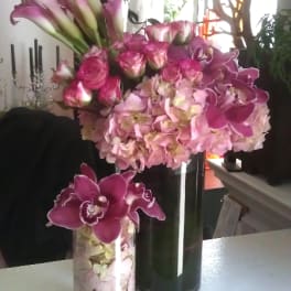 Pink calla lilies and orchids arranged in glass vases