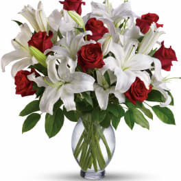 Red roses and white lilies arranged in a clear glass vase