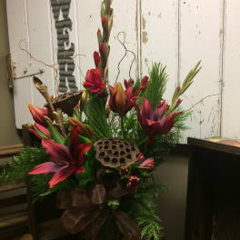 Tall floral arrangement with red lilies and greenery in a vase