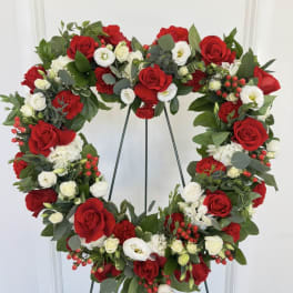 Heart-shaped floral wreath with red and white roses on a stand