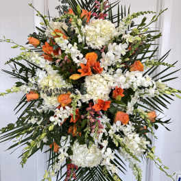 Large standing floral spray with white and orange flowers on a black easel