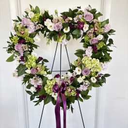 Heart-shaped floral wreath on an easel with a purple ribbon