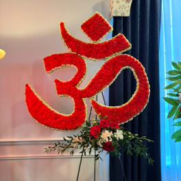 Large red floral Om symbol on a stand with roses at the base