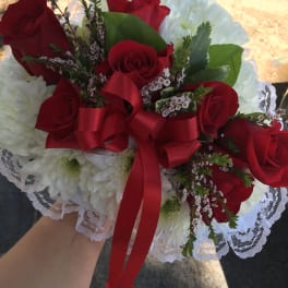 Red roses and white chrysanthemums in a lace-wrapped bouquet with a red ribbon
