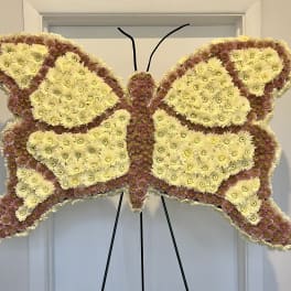 Butterfly-shaped floral standing spray with pale yellow and pink chrysanthemums