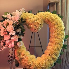 Heart-shaped floral wreath with pink roses and yellow carnations