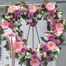 Heart-shaped floral wreath with pink gerberas and purple roses on an easel