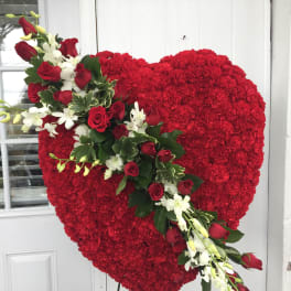 Heart-shaped red floral tribute with a diagonal spray of red roses and white orchids