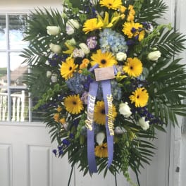 Large standing floral wreath with yellow daisies and blue flowers