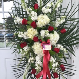 Standing floral spray with red roses, white blooms, and a red ribbon