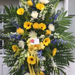 Large sympathy standing spray with yellow and white flowers and blue accents
