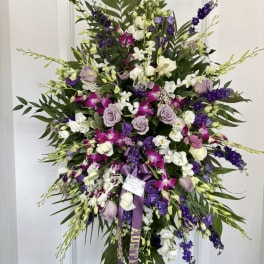 Large standing spray of purple, white, and pink flowers on a white easel