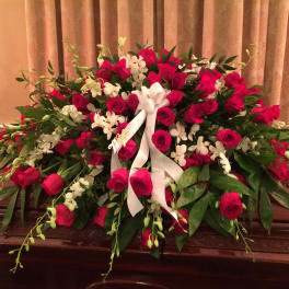 Large casket spray of red roses and white orchids with a white ribbon