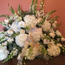Large white floral arrangement with roses and hydrangeas on a table