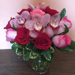 Pink orchids and red roses arranged in a glass vase