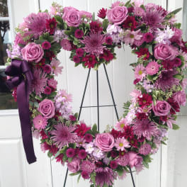 Heart-shaped floral wreath with pink and purple blooms on a stand