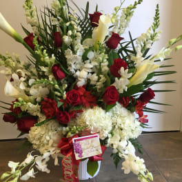 Large red and white floral standing arrangement in a white container
