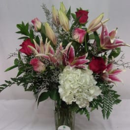 Pink lilies and roses with white hydrangea in a glass vase