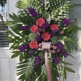 Large standing floral spray with pink gerbera daisies and purple flowers