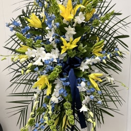 Tall standing floral spray with yellow lilies, white orchids, and blue flowers