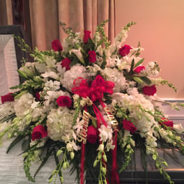 Large floral spray of white blooms and red roses with a ribbon bow