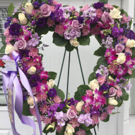 Heart-shaped floral wreath with purple, pink, and cream flowers on an easel