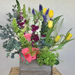 Mixed bouquet with pink roses, yellow tulips, and purple snapdragons in a wooden box