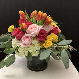 Mixed bouquet of roses, tulips, and hydrangea in a dark vase