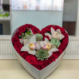 Heart-shaped box with red roses, white orchids, and succulents arranged tightly together