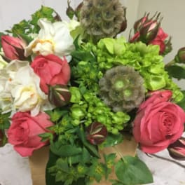Compact arrangement of pink roses, white blooms, and green hydrangeas in a small wooden box