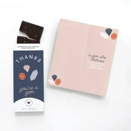 Sea salt caramel dark chocolate bar in thank you wrapper beside a pink gem-themed greeting card.