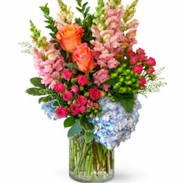 Mixed bouquet of roses, snapdragons, and hydrangeas in a glass vase