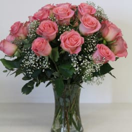 Pink roses arranged in a clear glass vase with baby's breath