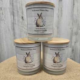 Three scented candles with rabbit labels stacked on burlap
