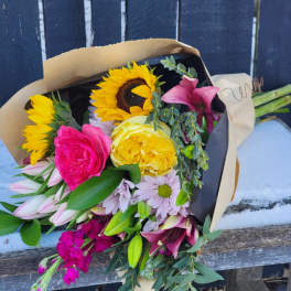 Bouquet of sunflowers, roses, lilies, and daisies wrapped in paper