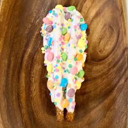 White chocolate-covered pretzel with colorful candy sprinkles