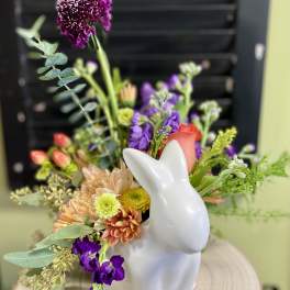 Mixed flower arrangement in a white rabbit vase
