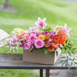 Mixed pink and orange flower arrangement in a rectangular box