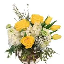 Yellow roses and white flowers arranged in a glass vase