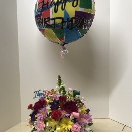 Birthday flower arrangement with a colorful balloon above mixed blooms