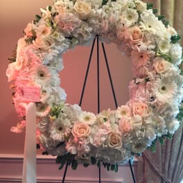 Large pastel floral wreath on a stand with roses and daisies