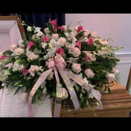 Large pink and white floral spray with ribbon on a casket