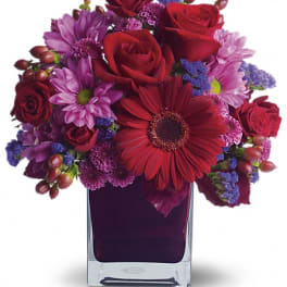 Red and purple mixed bouquet in a clear square vase